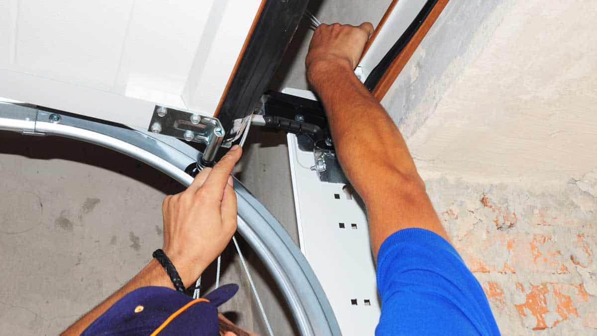 man repairing overhead garage door